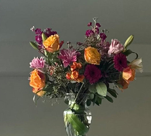 Bouquet of colorful flowers in a clear vase against a plain background