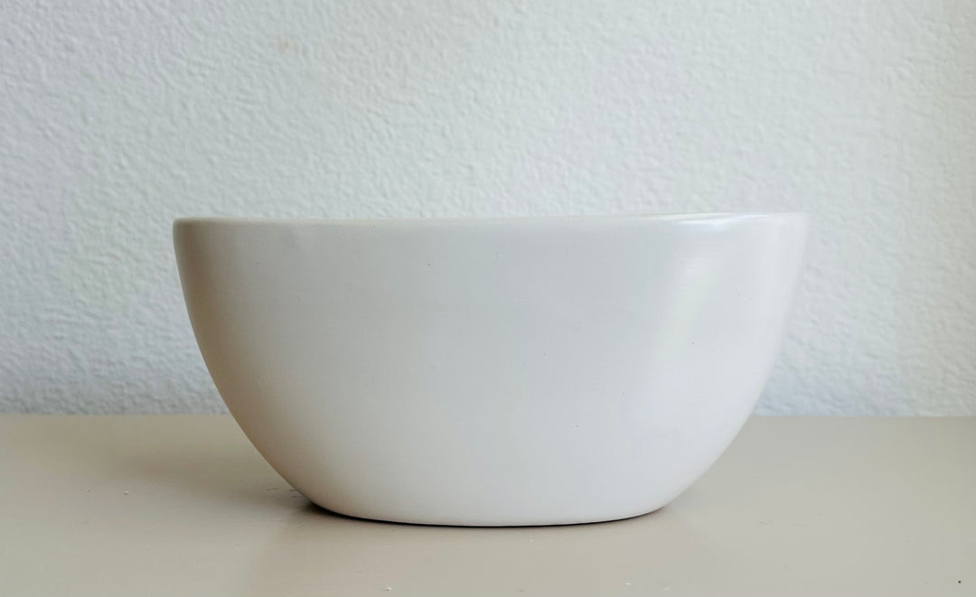 White ceramic bowl on a light surface with a light gray textured background