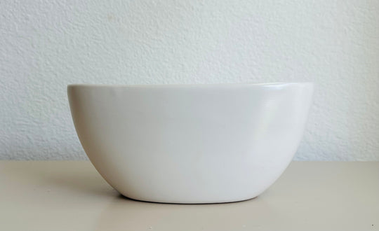 White ceramic bowl on a light surface with a light gray textured background